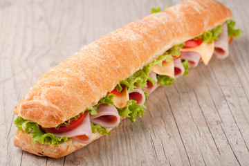Sandwich with bacon and vegetables on wooden table