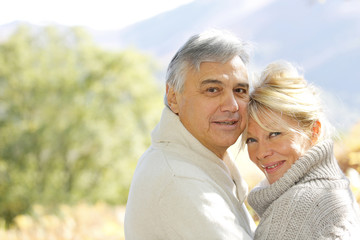 Senior couple embracing each other in countryside - obrazy, fototapety, plakaty