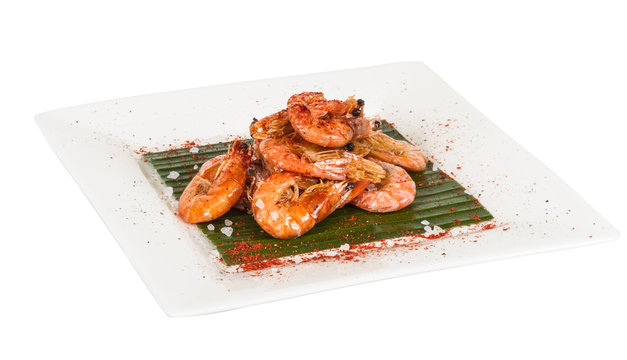 fried black tiger prawns with herbs and spices on banana leaf