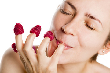 Young woman eating raspberries from fingers. © lichtmeister