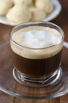Glass cup of coffee with froth with shortbread, selective focus
