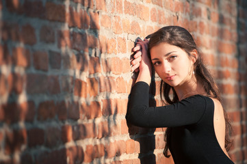 Young beautiful ballerina posing outdoors along a brick wall. 
