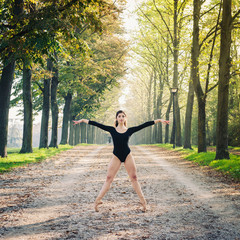 Young beautiful ballerina dancing outdoors in a parkway 