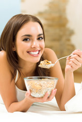 Young woman eating cereal muslin (flakes)
