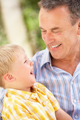 Fototapeta premium Grandfather And Grandson Relaxing On Sofa Together