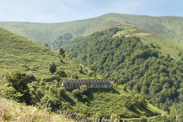 Abandoned concrete building (barracks) with mountains in backgro