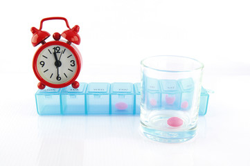 Pink tablet and redclok in daily pill box