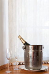 Champagne bottle in bucket with ice and two glasses of champagne
