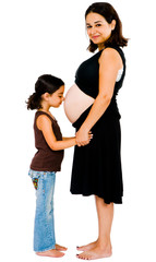 Girl kissing belly of mother