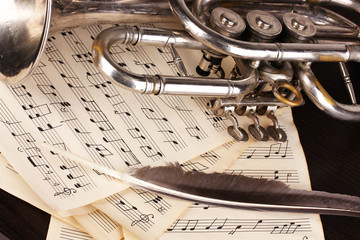 Obraz premium Musical notes and trumpet on wooden table