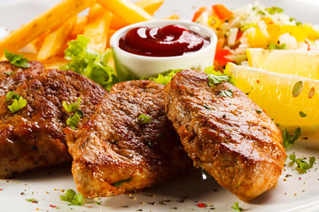 Grilled steaks, French fries and vegetables