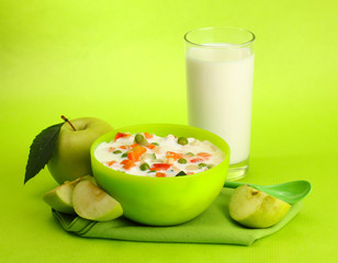 tasty dieting food and glass of milk, on green background