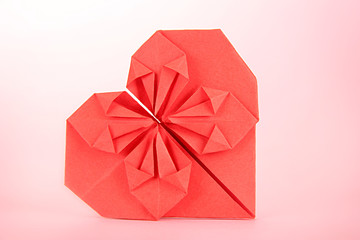 Origami paper heart on pink background.