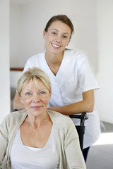 Fototapeta premium Nurse at home with elderly person in wheelchair