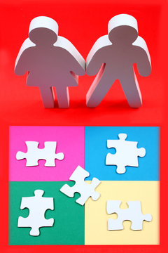 Male and female figures standing in front of puzzle pieces