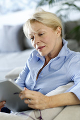 Senior woman using electronic tablet in sofa