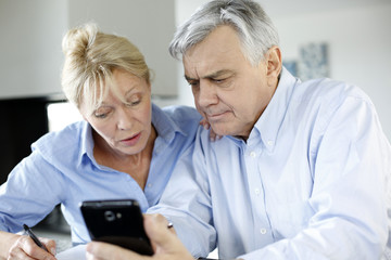 Senior couple calculting bills amount using smartphone