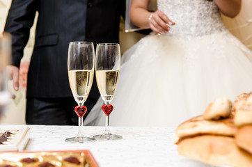 Glasses of champagne and bride and groom on background