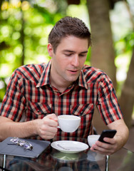 Business man sitting at table in cafe using mobile phone