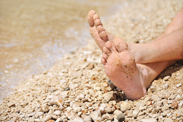 Relaxation on beach, detail of male feet
