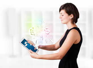 Young woman looking at modern tablet with currency icons