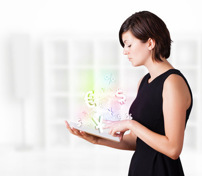 Young woman looking at modern tablet with currency icons