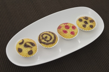 Four small cakes on a plate over a brown towel