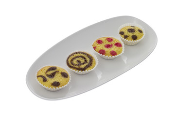 Four small cakes on a plate isolated over white
