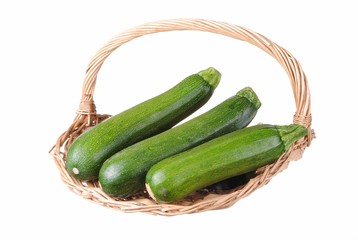 organic courgette in a straw basket, isolated on white