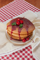 Pancakes with syrup and cherries on a plaid table cloth