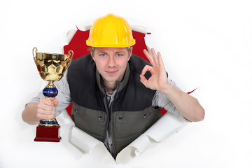 Builder with trophy making OK sign