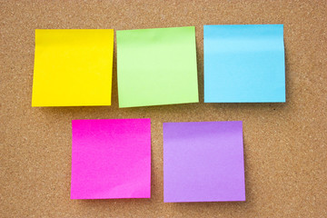 Wooden board with five blank colorful sticky notes.