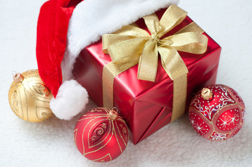 Gift box wearing Santa hat and Christmas balls, horizontal shot