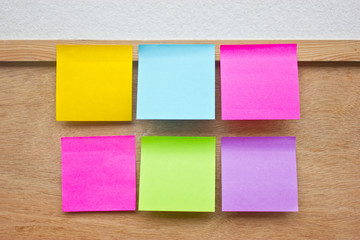 Six colorful sticky notes on wooden board.