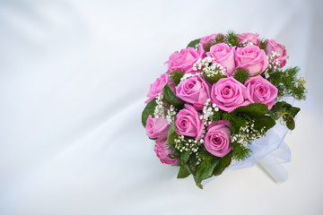 bouquet of pink roses on the white wedding dress