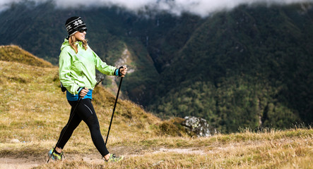 Woman hiker nordic walking in mountains