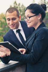 Couple of businessman and woman looking at tablet outdoors.