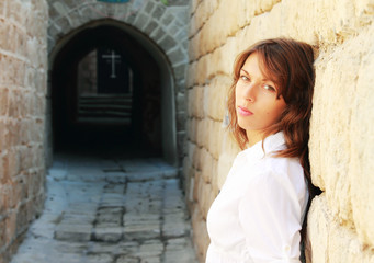 Fototapeta na wymiar young girl in a white shirt is standing against a stone wall. In