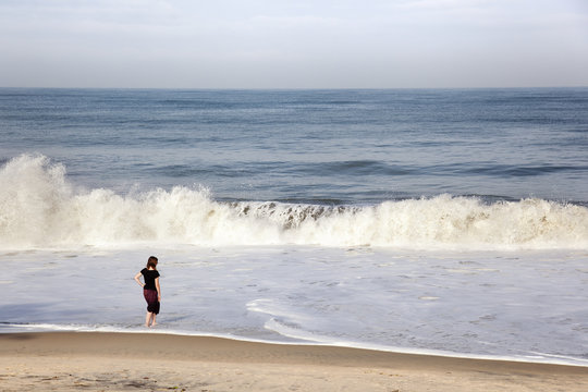 a girl on the beach as a wave breaks