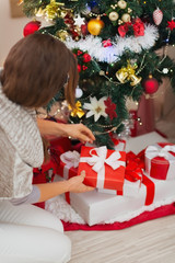 Woman putting present box under Christmas tree