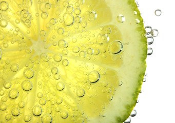 slice of lime in the water with bubbles, isolated on white