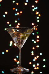 Martini glass and olives on dark bright background