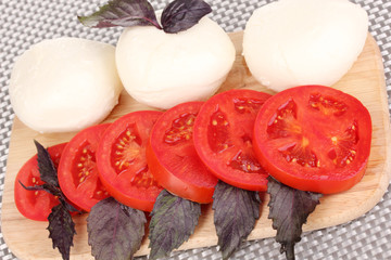 tasty mozzarella with tomatoes on chopping board close-up