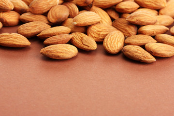 tasty almond nuts, on brown background