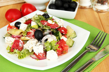 Fresh greek salad on plate on wooden table close-up