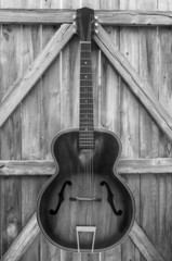 Monochrome Vintage Acoustic Guitar On Fence