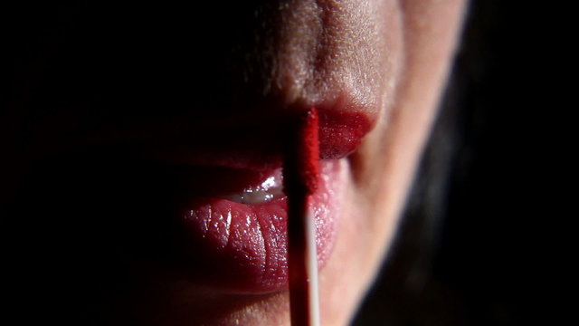 woman paints her lips with lipstick on a black background 2