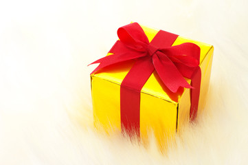 Gold gift on white fake fur background. (horizontal)