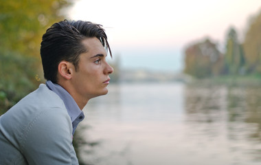 Good looking young man outdoors in nature (river, lake, trees)