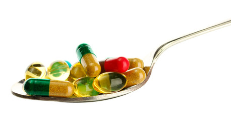 spoon with colorful capsules and pills, isolated on white